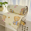 A cream-colored quilt featuring cute bear designs rolled up, displayed on a white surface.