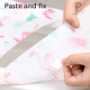 Hands are applying paste and fix to a pink and green patterned disposable toilet seat cover.