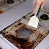 A hand uses a stainless steel scraper to remove residue from a cooking pan or surface.