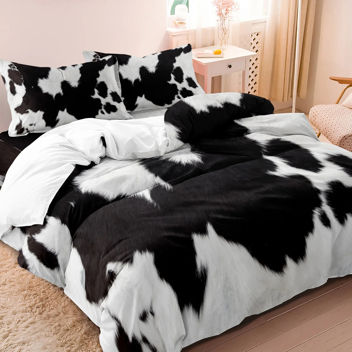 Black and white cow print duvet cover set with matching pillowcases on a bed.