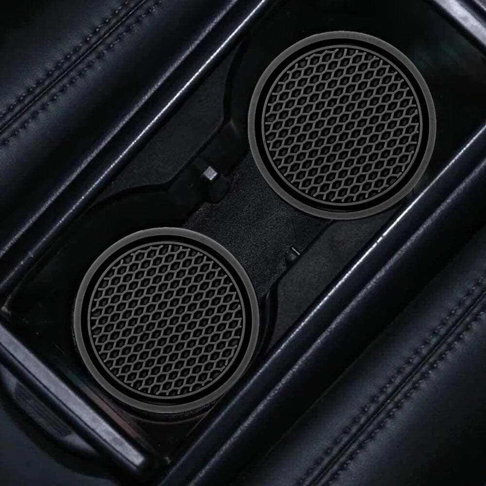 Gros plan de deux sous-verres anti-dérapants noirs pour porte-gobelets de voiture avec surfaces perforées à l'intérieur.