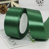A roll of dark green satin ribbon used for gift wrapping or DIY crafts, shown on a white surface.