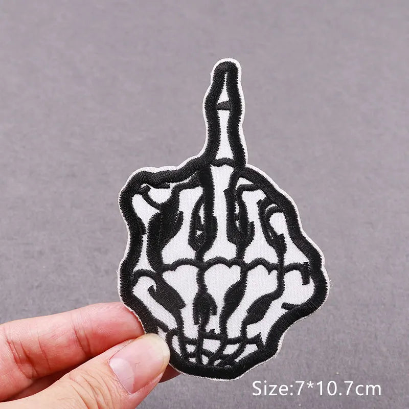 Black and white embroidered skull horror patch on a hand