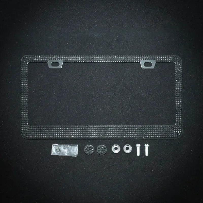 A clear crystal rhinestone license plate frame with mounting tabs and various rhinestone components.
