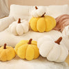 A collection of yellow and white plush pumpkin-shaped cushions and pillows arranged on a light-colored sofa.