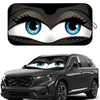 A cartoon folding car sunshade featuring an eye design placed on a black SUV.