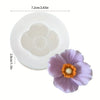 Un moule en silicone blanc avec une cavité en forme de fleur et une fleur violette épanouie.