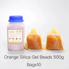 A bottle of orange silica gel beads next to ten sealed bags of orange silica gel beads.