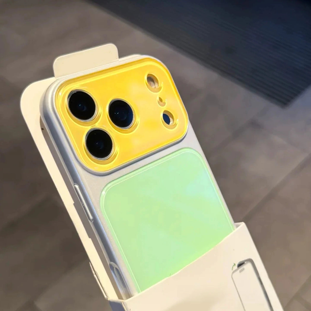A color blocking shockproof phone case featuring a yellow camera window and a light green back panel.