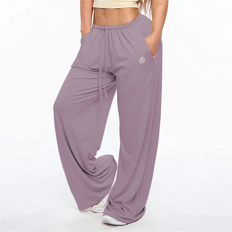 A woman wearing mauve flare leggings with a drawstring waist and a small logo on the thigh.