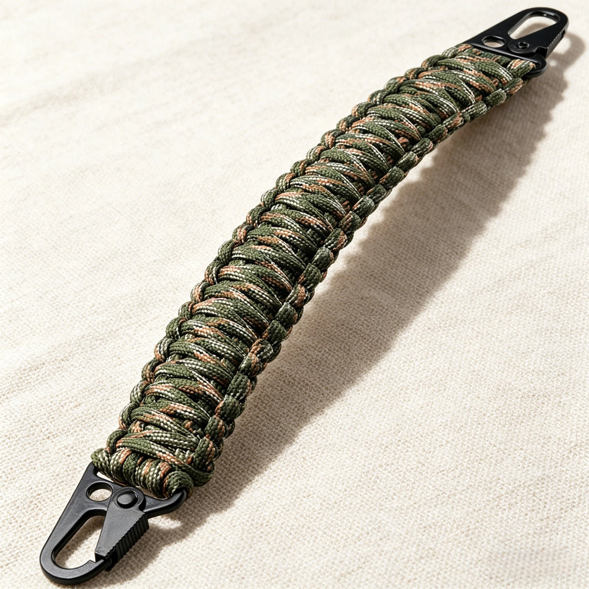 A close-up of a durable paracord handle with a metal hook, featuring a green and brown braided texture.