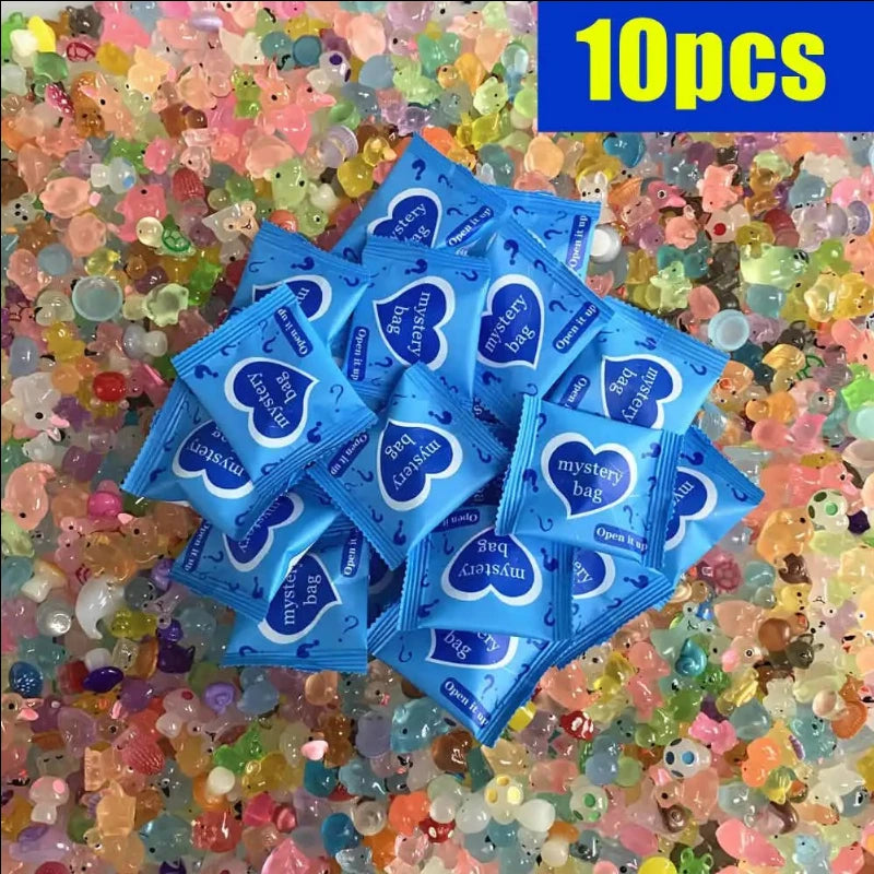 Haufen von zehn blauen Überraschungstüten mit Geheimbeutel-Design auf einem Bett aus farbenfrohen, leuchtenden Plastikperlen.