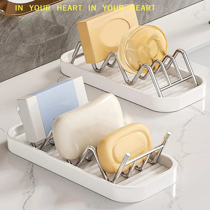 A set of W-shaped stainless steel soap holders with drainage trays in yellow and white on a marble surface.
