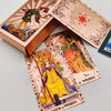 A deck of gold foil tarot cards and a guidebook are displayed in open packaging.