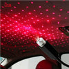 A portable LED projection lamp is shining red stars onto a car's interior ceiling.