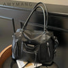 Black soft leather plaid crossbody bag with adjustable strap displayed on a dark surface.
