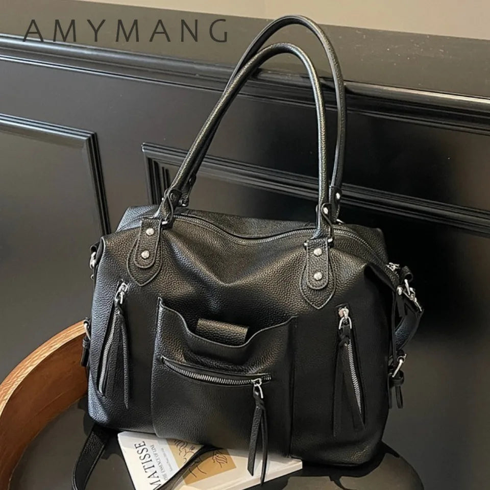 Black soft leather plaid crossbody bag with adjustable strap displayed on a dark surface.