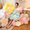 A collection of yellow and pink fluffy sunflower plush pillows displayed on a wooden floor.