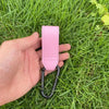 A hand holds a pink PU leather baby bag organizer with a hook for a stroller.
