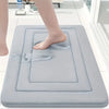 A person's foot is placed on a gray absorbent soft non-slip bath mat for foot soaking or massage.