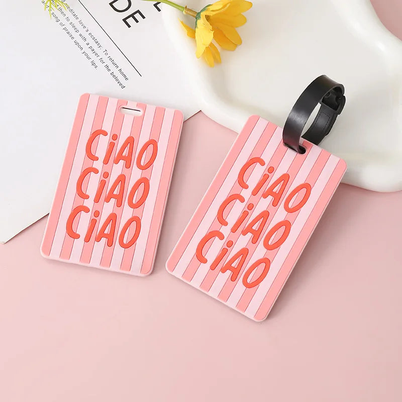 A pink silicone luggage tag with the word CIAO embossed in orange text is shown next to a black strap.