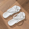 A pair of white foldable EVA travel slippers lying on a wooden surface.