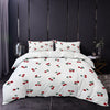 White duvet cover set with a red cherry print and matching pillowcases displayed on a bed.