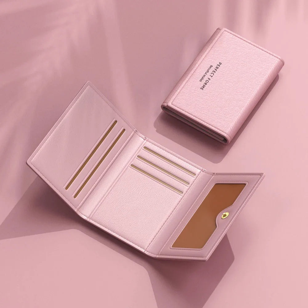 A pink leather card holder wallet with multiple slots shown open on a light pink surface.