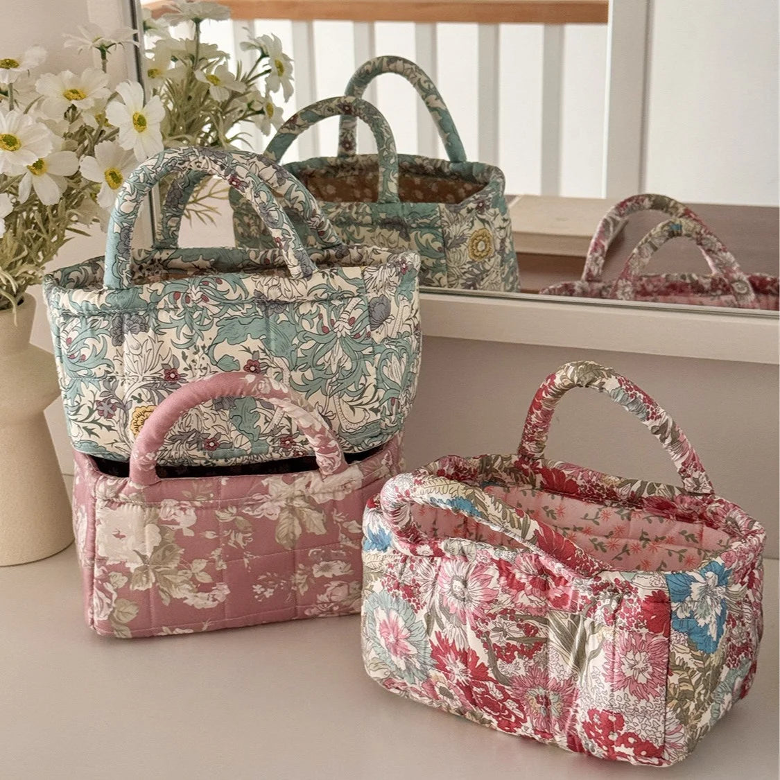 A collection of quilted fabric storage baskets in various floral patterns and colors displayed on a shelf.