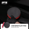 A hand wearing a black glove is holding a black clay pad for car wash paint detailing.