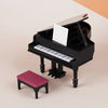 A black 1:12 scale dollhouse piano with a bench and music stand on a light background.