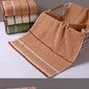 A set of three folded bath towels in shades of green, beige, and white cotton.