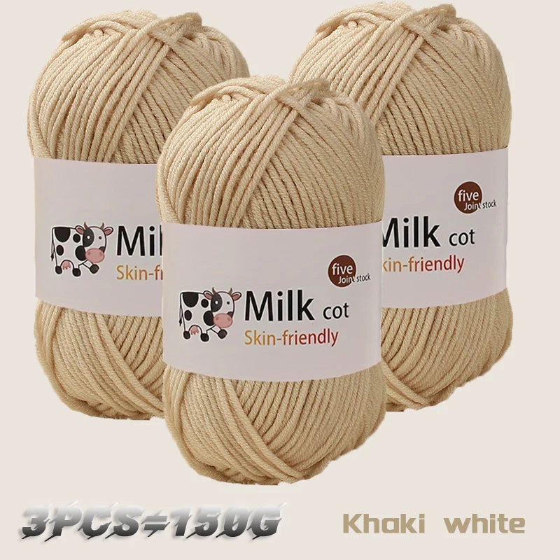 Three skeins of light beige or khaki colored acrylic yarn labeled Milk cot skin-friendly for knitting and crochet