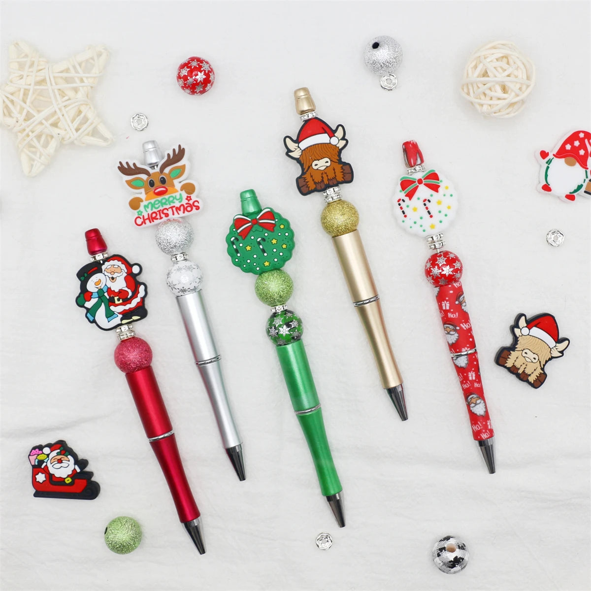 A craft kit featuring a beaded ballpoint pen and various Christmas-themed beads like reindeer and snowflakes.