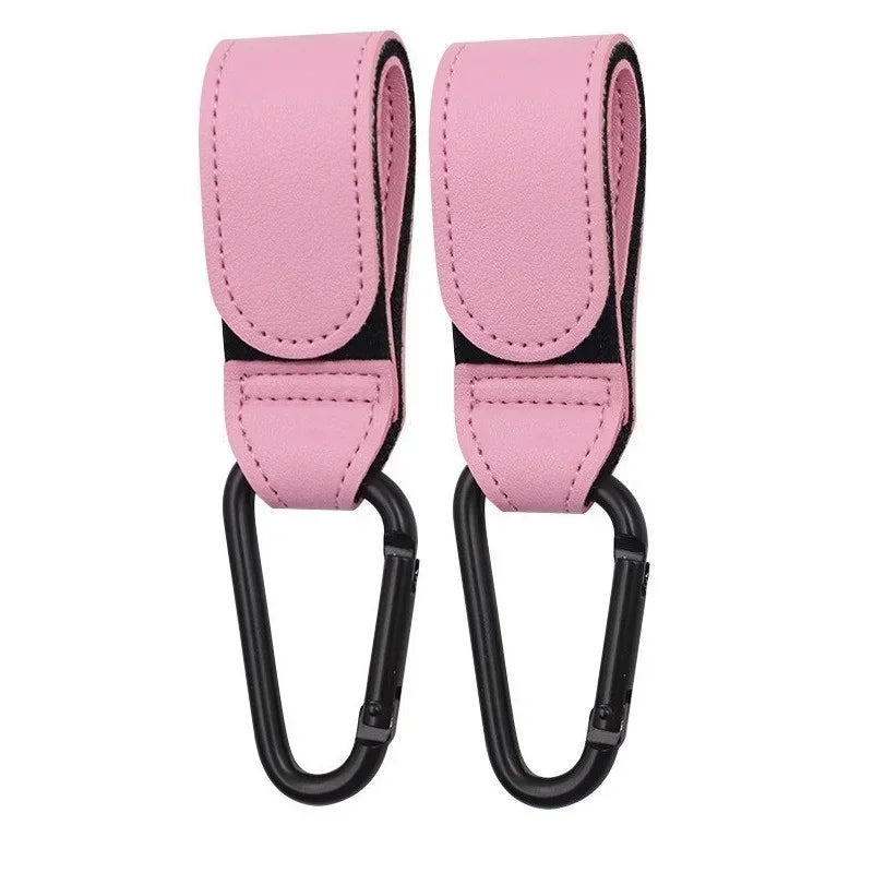 A pair of pink PU leather stroller hooks with black accents for organizing baby bags.