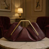 A deep burgundy soft PU leather crossbody bag resting on a marble table in a warmly lit room.