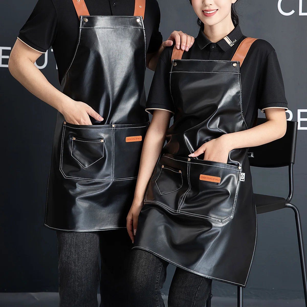 A woman wearing a black PU leather multi-pocket kitchen apron, standing in front of a dark background.