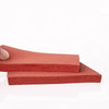 A stack of red silicone heat-resistant craft mats lying on a white surface.