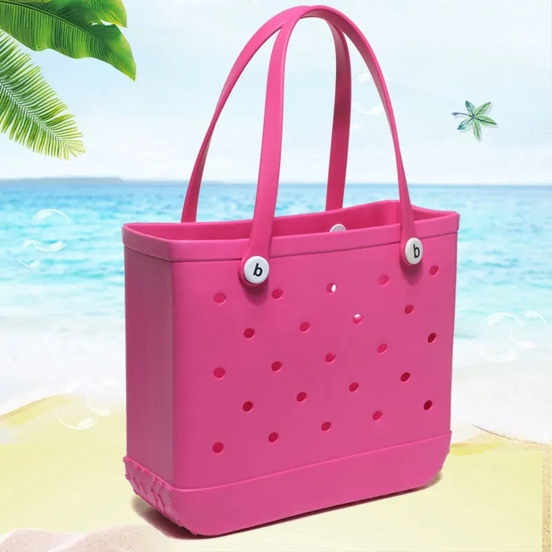 Helle pinke, tragbare EVA-Strandtasche mit perforierten Seiten an einem Sandstrand am Ozean.