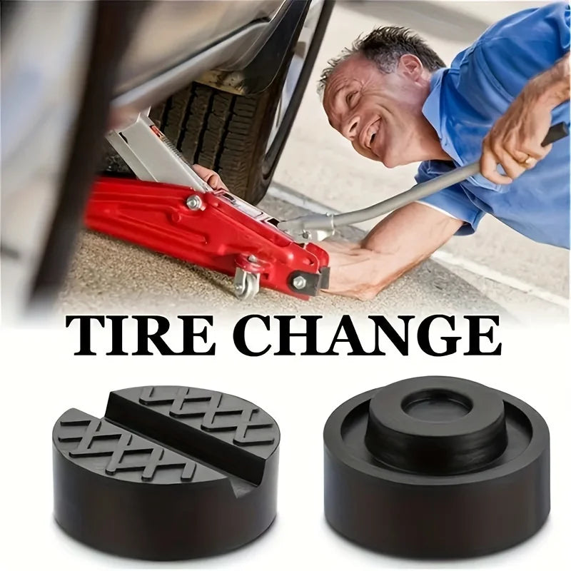 A close-up of a person performing a tire change using a red floor jack and rubber pad on the ground.