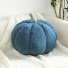 A round, fuzzy blue Halloween pumpkin plush pillow resting on a white linen fabric.