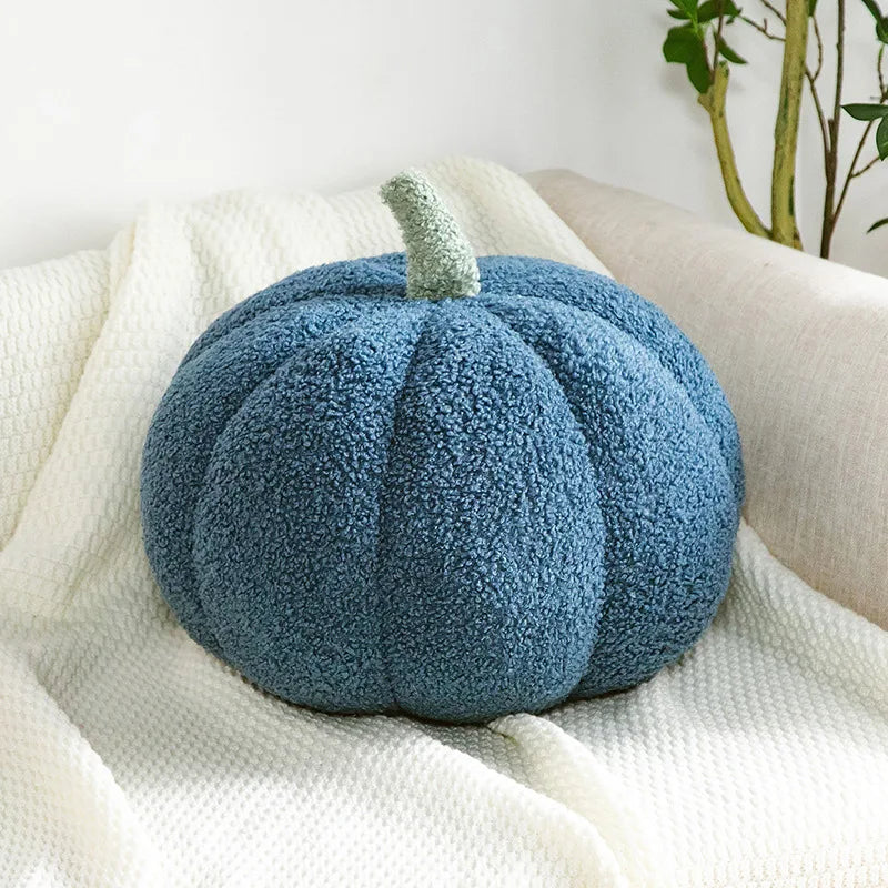 A round, fuzzy blue Halloween pumpkin plush pillow resting on a white linen fabric.