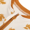 Close-up of a white baby sleep sack with gold leaf pattern and a tan zipper detail.