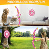A girl is using a pink bow and arrow set outdoors in a grassy park.