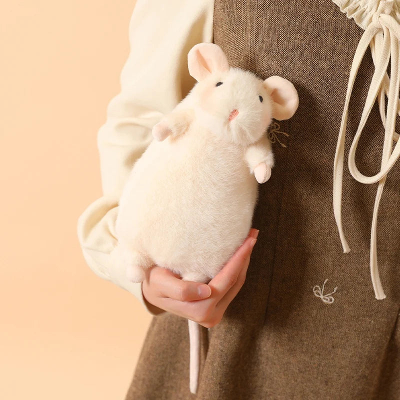 A small, fluffy white rabbit plush toy is being held by a hand against a brown fabric background.