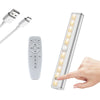 A rechargeable LED under-cabinet light fixture with a remote control and touch sensor being activated by a hand.