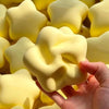 A hand is squeezing a yellow, star-shaped stress relief toy made of soft, squeezable material.