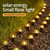 Solar LED garden pathway lights embedded in dark gravel with glowing yellow lights.