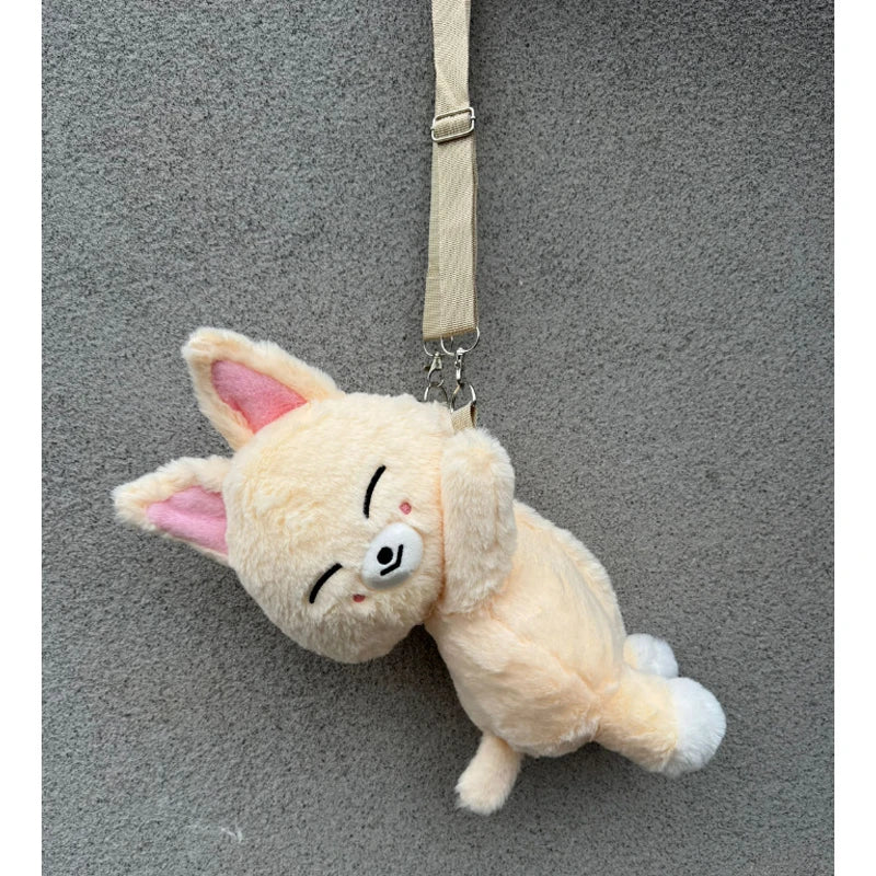 A soft, light orange K-pop character animal plush doll with pink ears hanging from a strap.