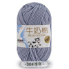 A ball of gray milk cotton blend yarn with a label showing the name and thread count.